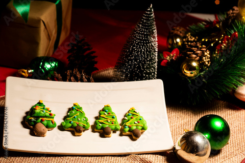  gingerbread cookies in the shape of a Christmas tree with a background of Christmas lights and decorations