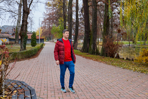 A middle-aged man walks through the park in the morning and relaxes on a late autumn day.