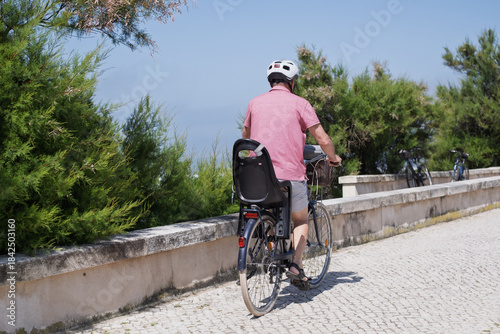 Elderly Man with Mustache and Helmet Riding a Bicycle