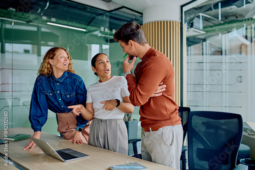 Canvas Print Three colleagues engaged in a lively discussion at office, sharing insights and