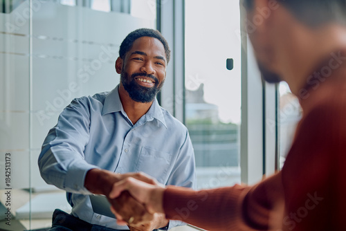 Diverse businessmen shaking hands and smiling during a meeting, celebrating a successful deal and new professional partnership