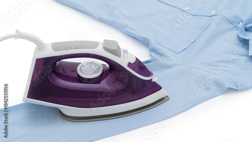 beside view of purple electric iron placed on light blue shirt while ironing