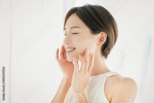 顔を触っている笑顔の若い女性