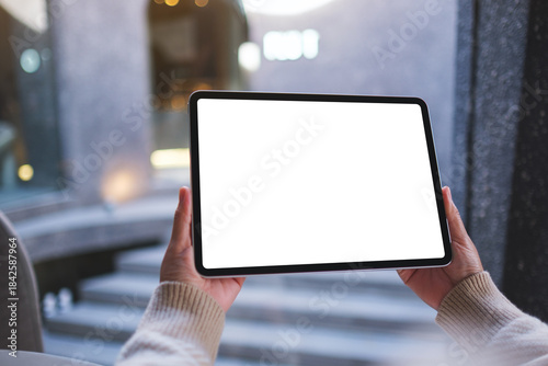 Mockup image of a woman holding digital tablet with blank white desktop screen in cafe