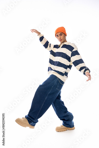 Stylish teenager showcases trendy outfit with vibrant orange hat and striped polo