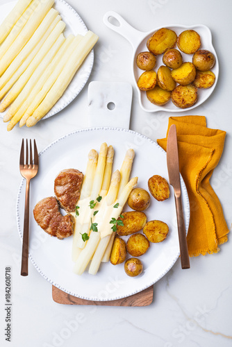 Grilled german white asparagus with pork tenderloin medallions, baked new baby potatoes, hollandaise sauce