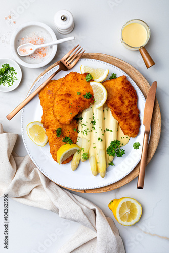 White asparagus with fried schnitzel, lemon and hollandaise sauce