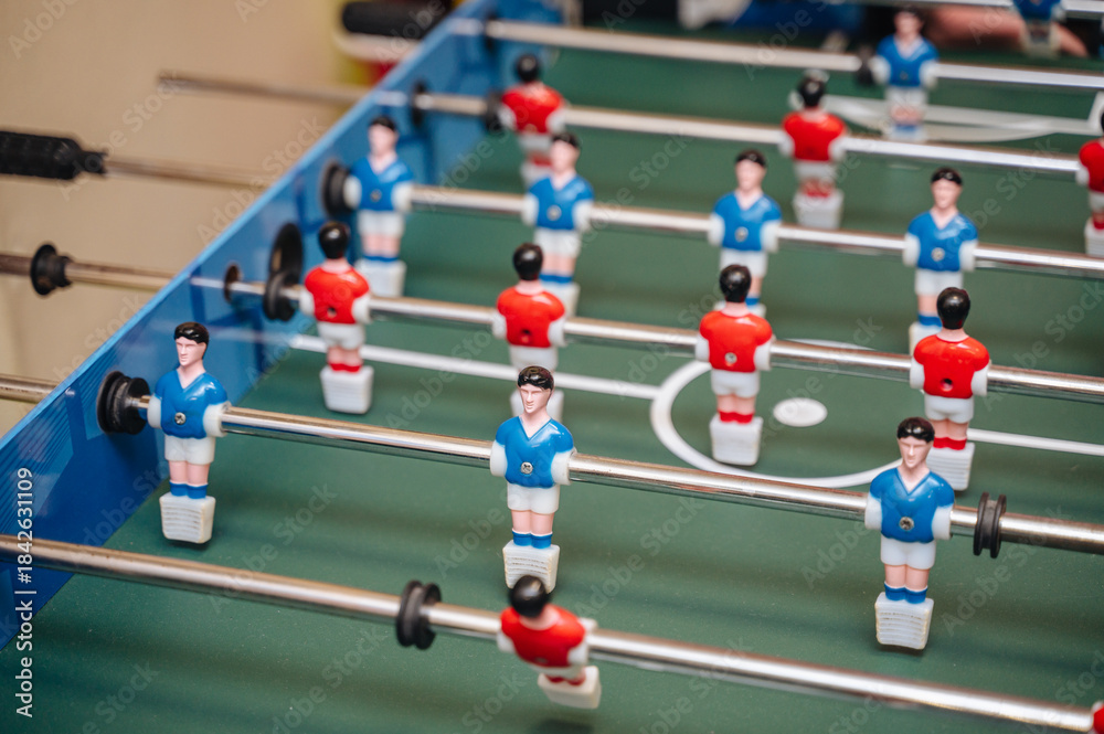 Fototapeta premium Close-up of players on a table football game (foosball), symbolizing competition, teamwork, and leisure activity