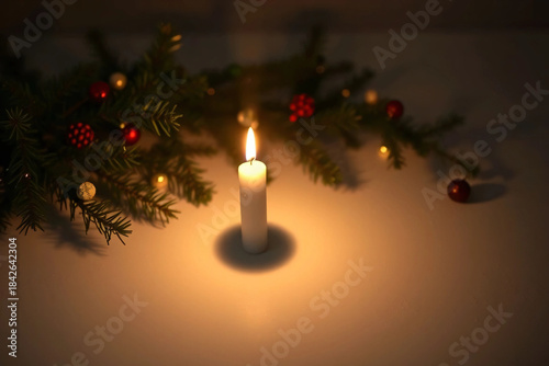 Serene Holiday Scene: A Single Candle Amidst Festive Greenery and Ornaments