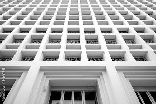 Low-angle shot of a white building facade with repetitive square windows, minimalist