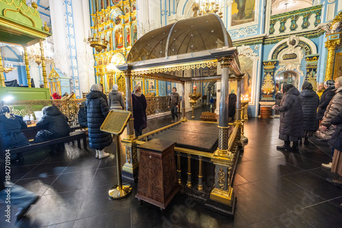 View of a gilded shrine stands centered amidst a reverent gathering, its ornate details contrasting against the cool, blue-toned walls, Istra, Moskovskaya oblast', Russia.