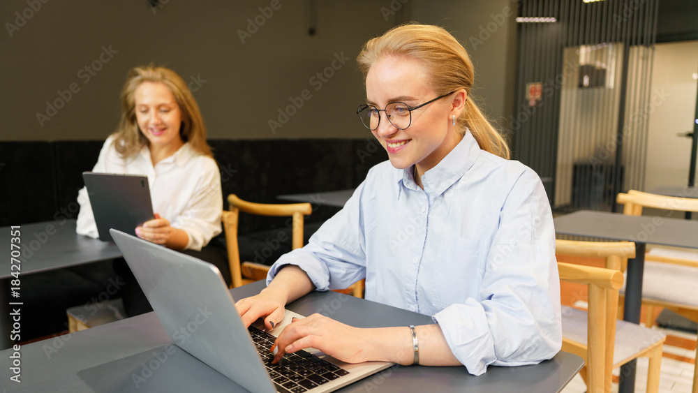Obraz premium Two women working at a table with laptops