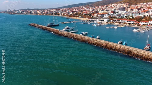 Wallpaper Mural Blue sea water splashes by the stone dam with a berth for boats. Cityscape of Sveti Vlas, Bulgaria at the shore at backdrop. Aerial view. Torontodigital.ca
