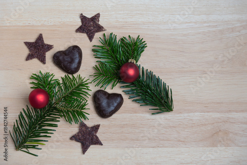 Gingerbread hearts with Christmas tree balls, fir branches and stars on wooden surface