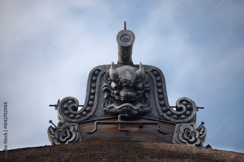Obraz premium An ancient Japanese temple roof is adorned with an Onigawara carved with striking detail