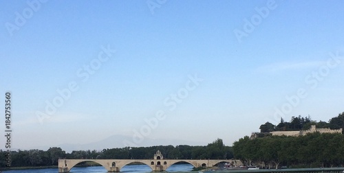 Panoramic View of the Historic Pont Saint-Bénézet (Avignon Bridge) Over the Rhône River in Provence, France, with Arches and Chapel Against a Wide Blue Sky and Green Trees, Capturing European Landmark