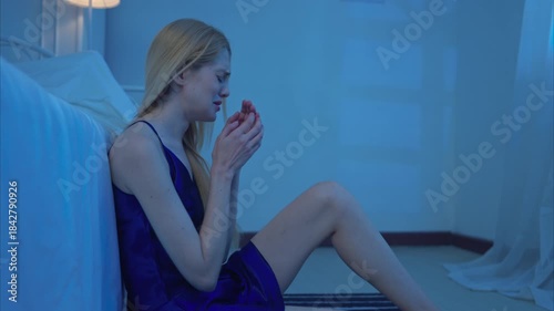 A young woman in blue pajamas feels sad after receiving information from her phone before going to bed on a night with a blue moon