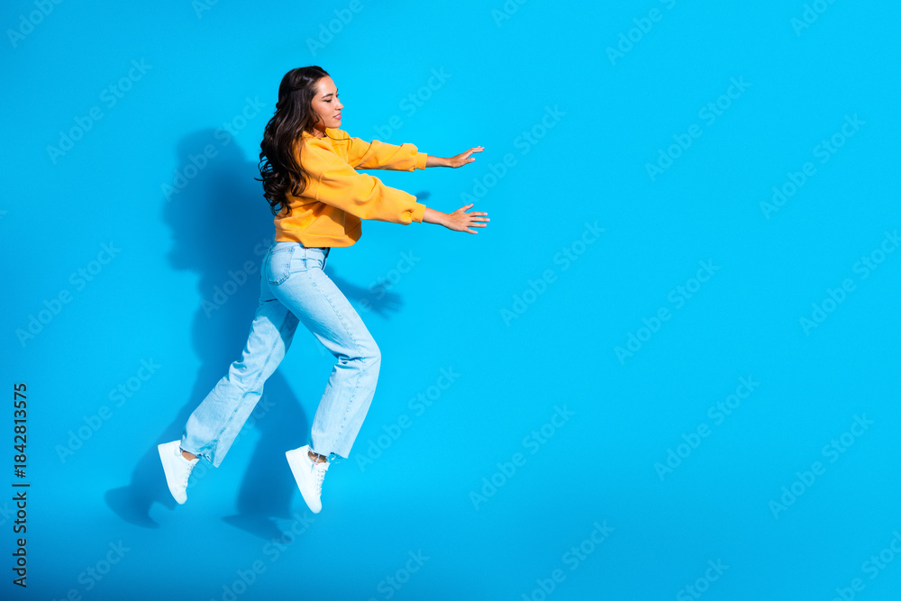 Fototapeta premium Young mixed race woman jumps in a yellow sweater on blue background lifestyle fashion