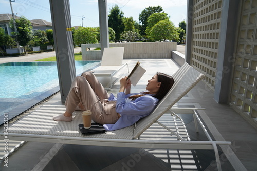 Wallpaper Mural Young woman reading book and relaxing on sunbed outdoor Torontodigital.ca