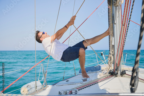 Obraz na plátně sailing instructor uses his full body weight to pull the sails of a sailboat, pr