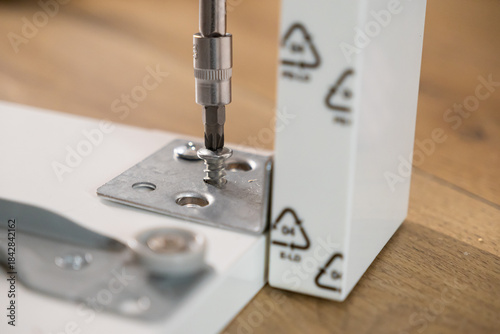 Fotografi Screwdriver bit precisely fastening a shiny metal screw into a sturdy bracket on