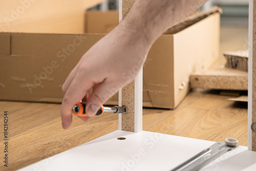 Wallpaper Mural Person's hand uses a screwdriver to assemble new flat-pack furniture at home, symbolizing a practical DIY home improvement project and a fresh start Torontodigital.ca