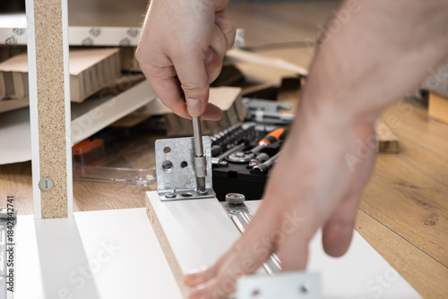 Wallpaper Mural Close-up of hands diligently assembling furniture, fastening a metal bracket with a screwdriver onto wooden panel, representing practical DIY home improvement skill Torontodigital.ca