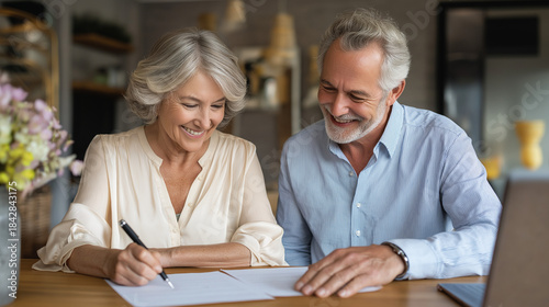 A happy senior couple signing legal or financial documents together at a table