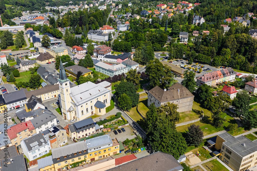 Fototapeta premium Aerial drone view of Jesenik town in Czech Republic showcasing the central market square and historic buildings nestled in Jeseniky Mountains, panoramic urban landscape in sunny summer day