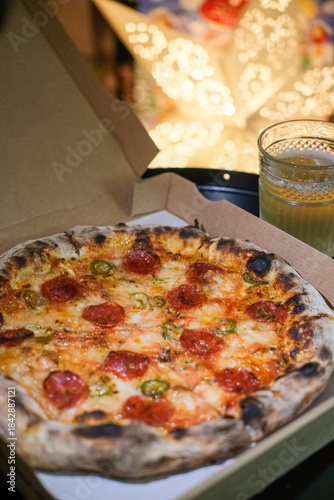 A pepperoni pizza a take away box at home, Christmas decorations on the background 