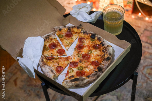 A pepperoni pizza a take away box at home, Christmas decorations on the background 