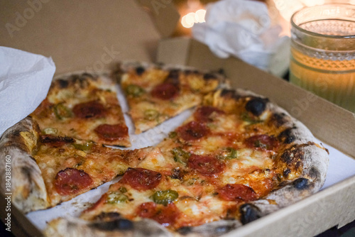 Take away pepperoni pizza on a table at home, cosy Christmas light 