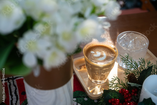 Close up of Hot coffee latte with latte art milk foam in cup mug with Xmas decors and Xmas tree baubles on wood desk Celebrating Merry Christmas and New year,Merry x-mas
