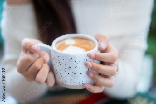 Close-up of hands Holding cup mug of Hot coffee latte decorating to a Christmas tree at home in the living room indoors in coffee shop Decoration During Christmas x-mas and New Year holidays.