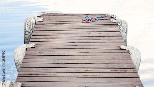 Fotografie A picturesque wild pier on a forest lake in close-up with clear blue water