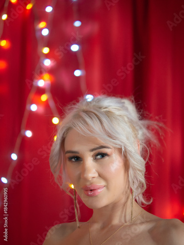 Blonde, blue-eyed woman in a red Santa Claus dress, Christmas theme in the studio.
