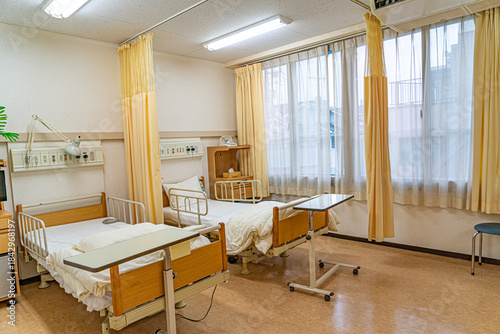 Fotografie 明るい窓辺の病室に並ぶ二つのベッドを撮影した医療ケア空間／Bright twin-bed hospital room with daylight for pat
