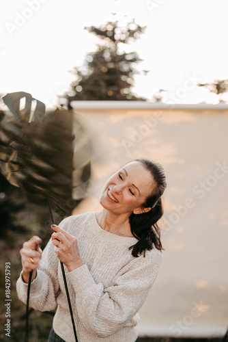 Dunkelhaarige Frau mit Palmenblättern vor Studiohintergrund in freier Natur