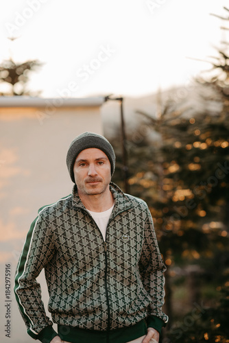 Mann in grüner Weste vor beigem Studiohintergrund in freier Natur