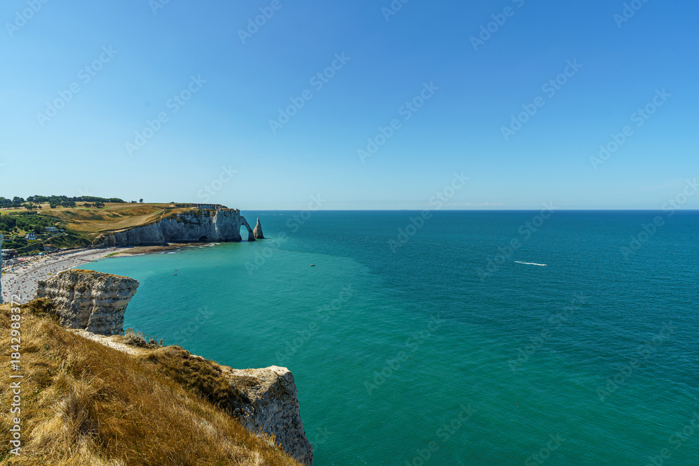 Fototapeta premium Great view of Stone cliffs and large rocks against the backdrop of ocean water in the Etretat in Normandy, France The water and sky are blue and transparent The weather is clear