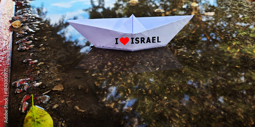 Paper boat with the inscription I love Israel floating in a puddle. Photo concept: rain in Israel, rainy weather, flood, autumn, winter