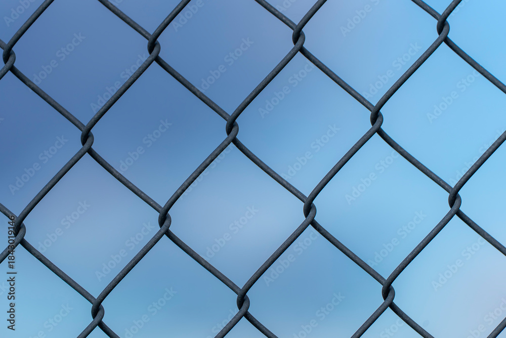 Fototapeta premium Close up of a chain link metal fence with blue sky background