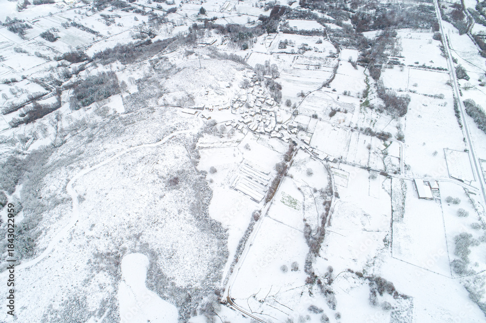 Fototapeta premium Aerial View of a Small Village Surrounded by Snow Covered Fields The Concept of Isolation