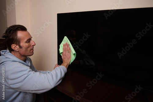Man Cleaning Television Screen With Soft Cloth In Living Room For Sparkling Surface