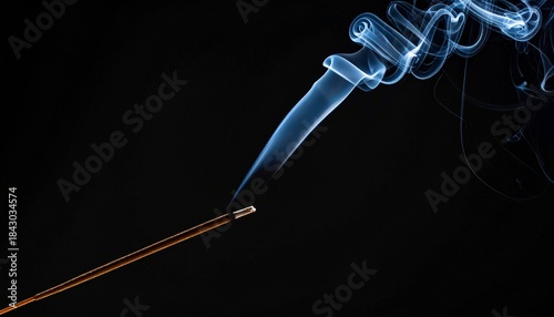 Burned Out Incense Stick. Thin trail of smoke rising from a recently burned incense stick, black background.