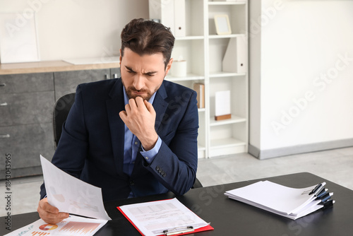 Angry businessman with paper at table in office