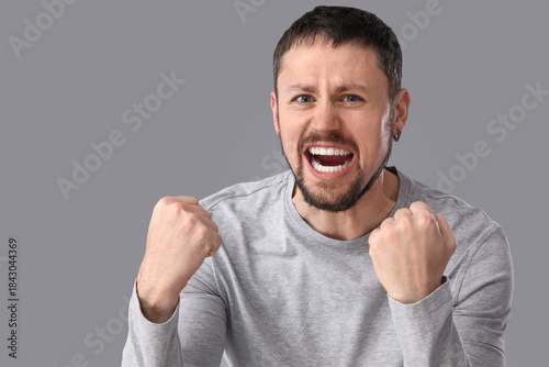 Young man screaming on grey...