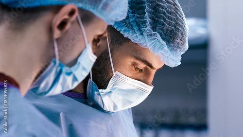 Obraz na plátne Medical professionals in surgical attire, focused on a procedure, wearing masks