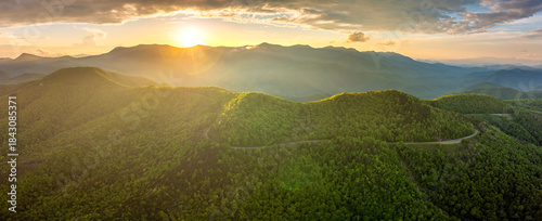 Winding parkway road near Mount Mitchell in mountain forest with green canopies in summertime evening. Driving in North Carolina wild woods nature in summer