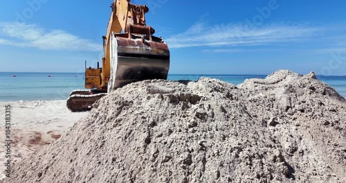 close up of a excavator digging sand on a beach near the ocean. ( in slow motion)